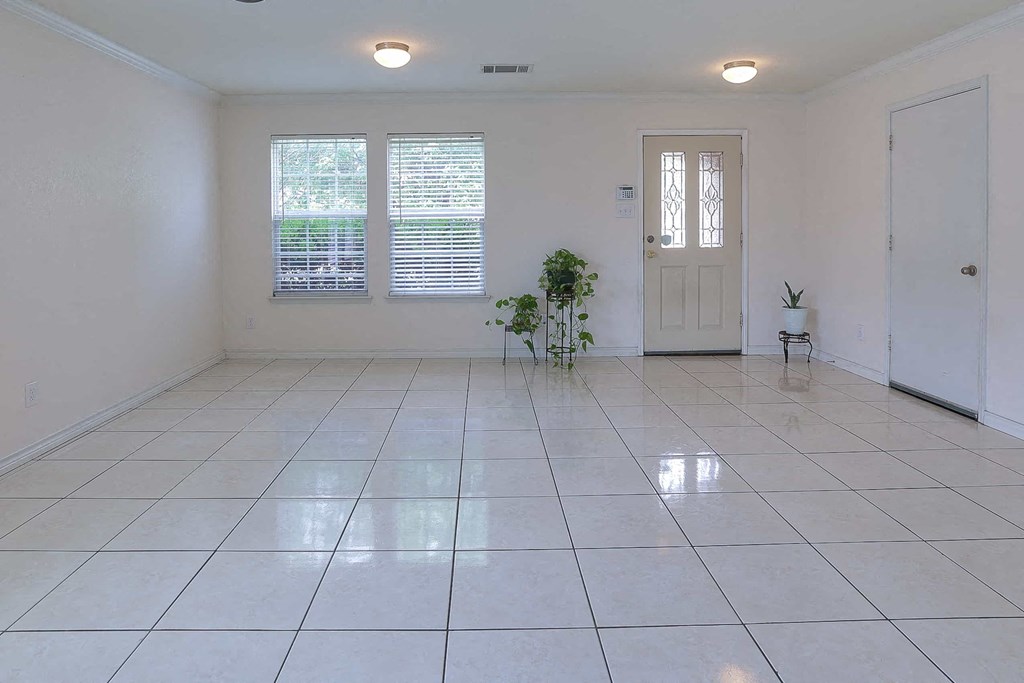an empty living room with a white tiled floor and a white door