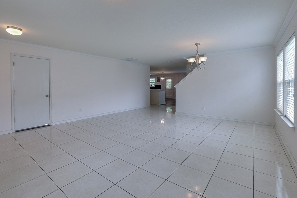 an empty living room with a tile floor and white walls