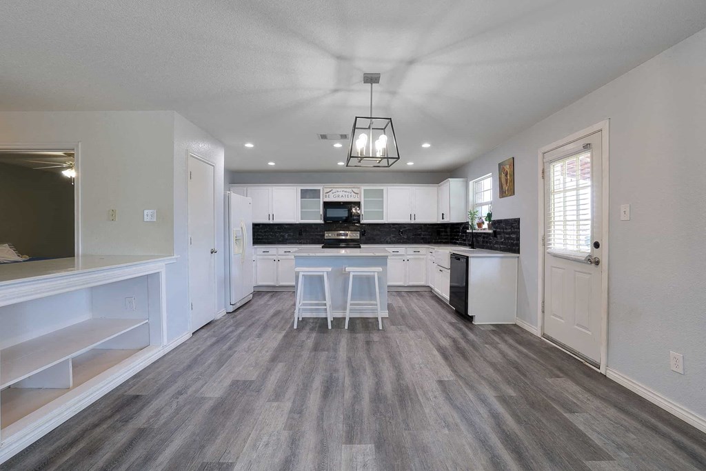 a kitchen with white cabinets and a black counter top
