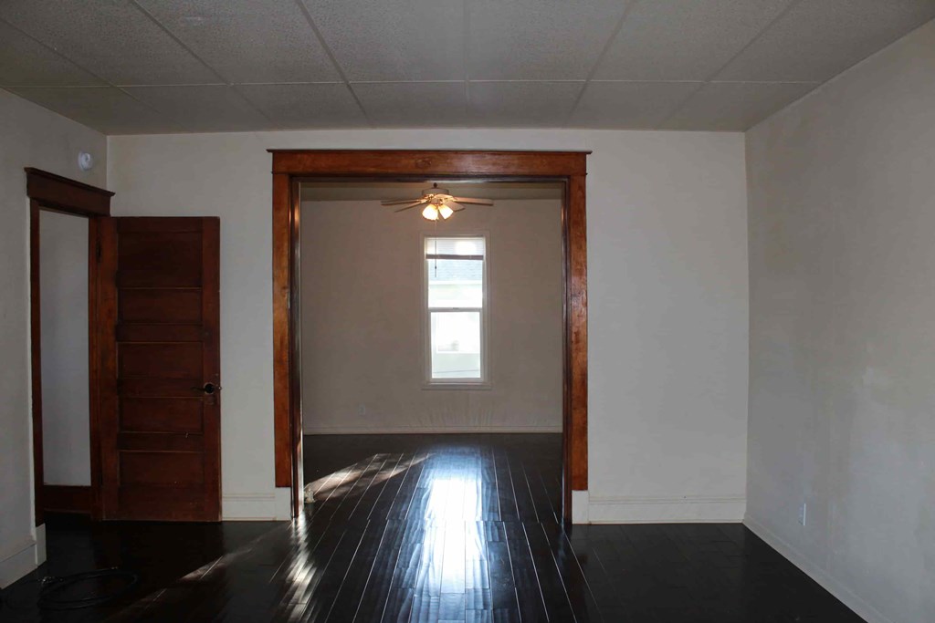 an empty living room with wood floors and a window