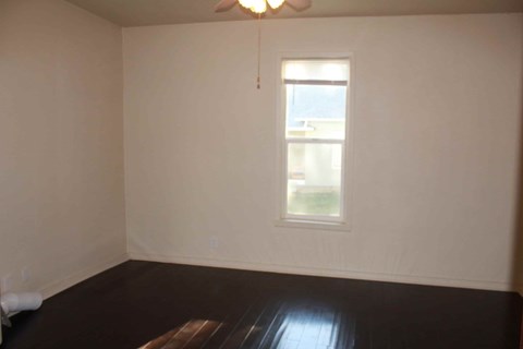 an empty room with a window and wooden floors
