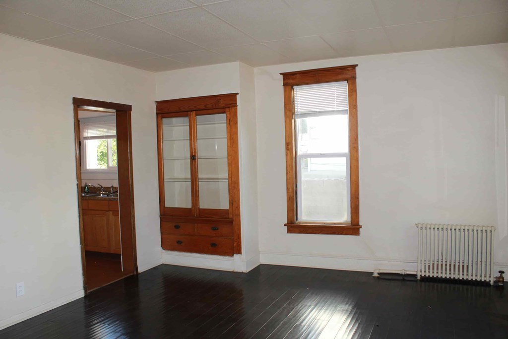 an empty living room with white walls and a dark wood floor