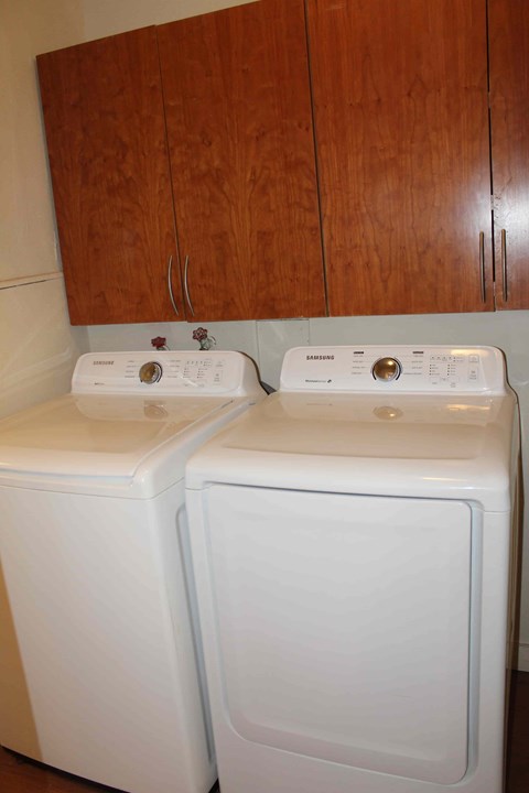 a white washer and dryer in a kitchen with wooden cabinets