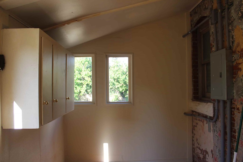 a room with two windows and a cabinet on the wall