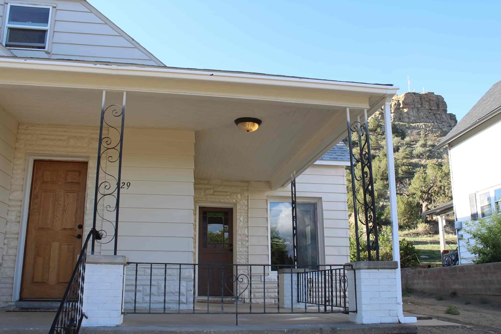 a house with a porch and a mountain in the background