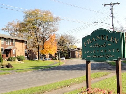 A sign for Franklin Park Apartments stands in front of a building.