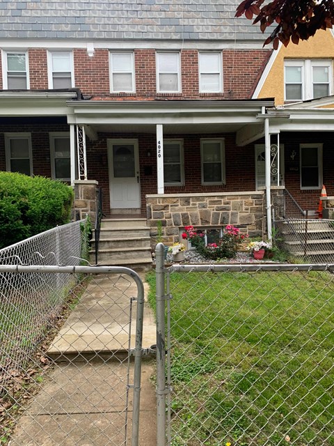 A house with a white porch and a chain link fence.