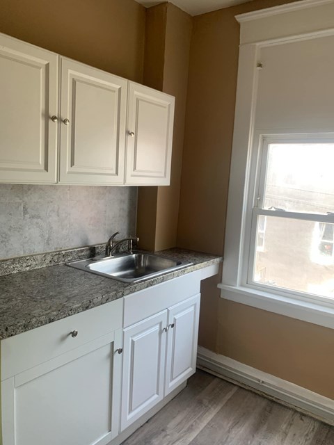 A kitchen with white cabinets and a granite countertop.