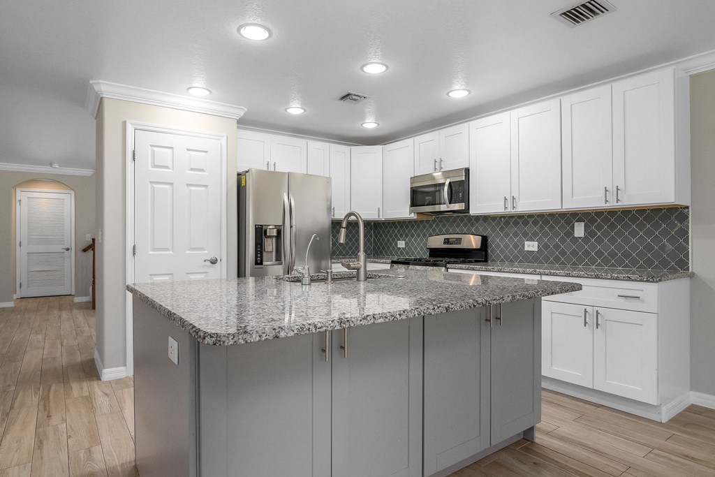 a kitchen with white cabinets and a granite counter top