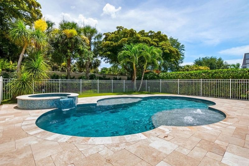 a pool and spa in a backyard with a fence