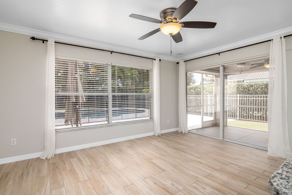 an empty living room with a ceiling fan and sliding glass doors to a patio