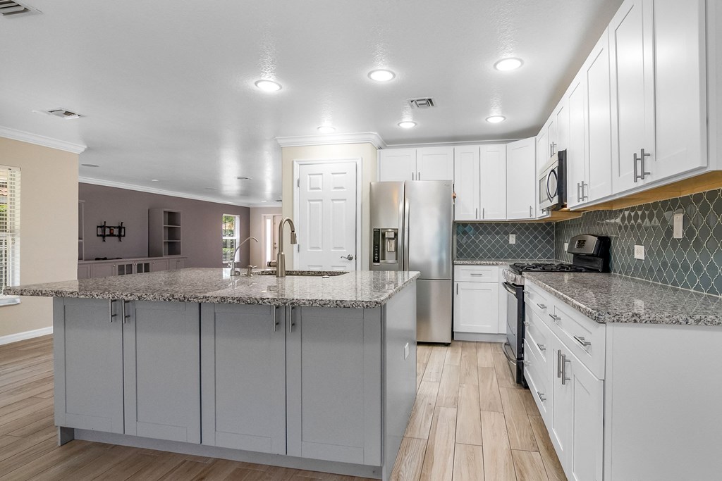 a large kitchen with white cabinets and granite counter tops