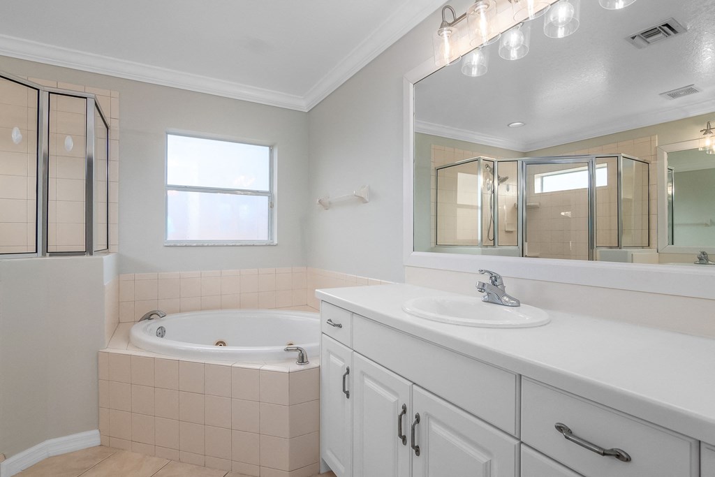 a white bathroom with a tub and a sink and a mirror