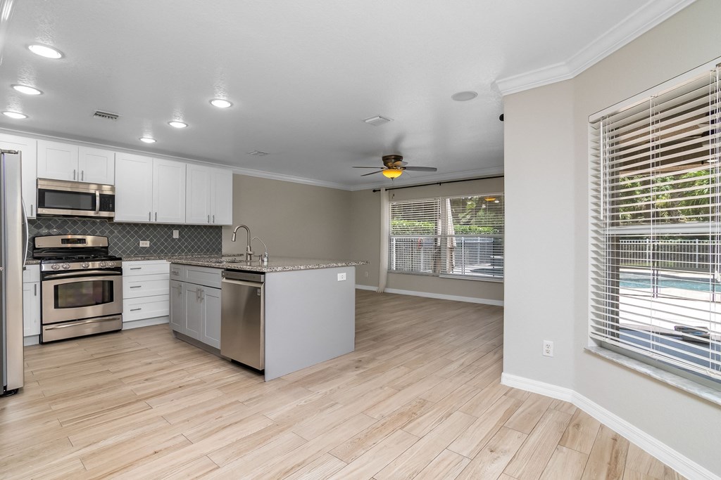 an empty kitchen with stainless steel appliances and a large window