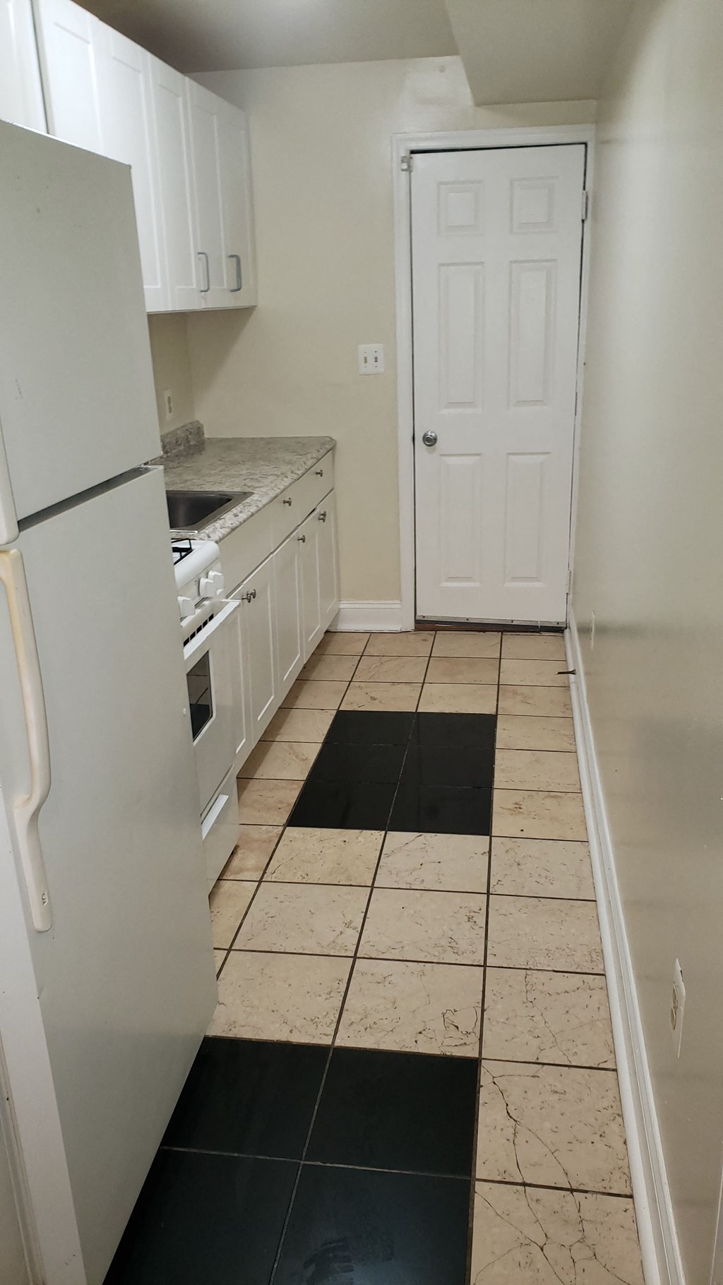 a kitchen with white cabinets and a refrigerator and a door