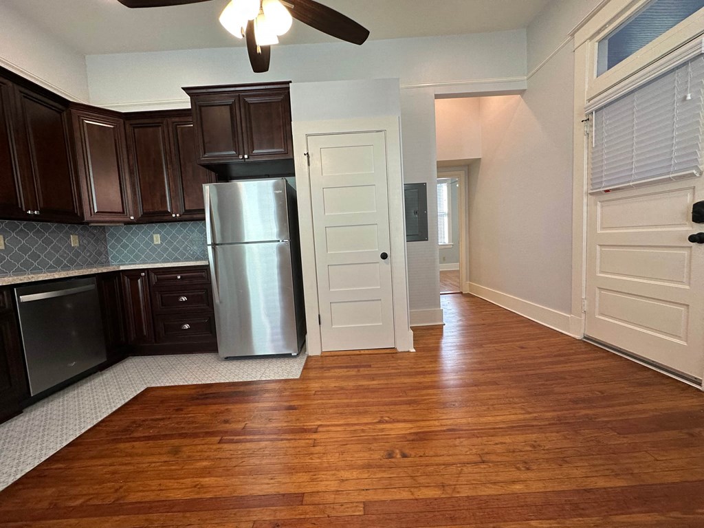 a kitchen with wood floors and a stainless steel refrigerator