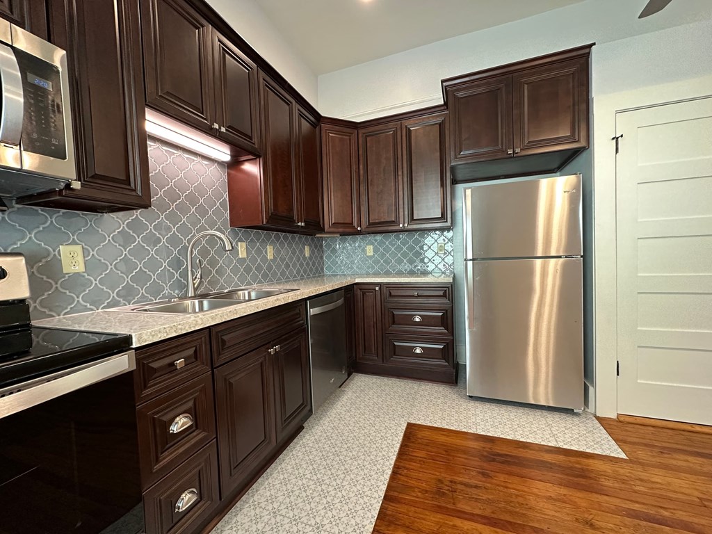 a kitchen with dark wood cabinets and a stainless steel refrigerator