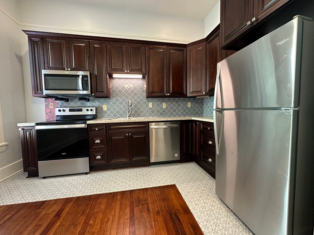 a kitchen with stainless steel appliances and dark wood cabinets