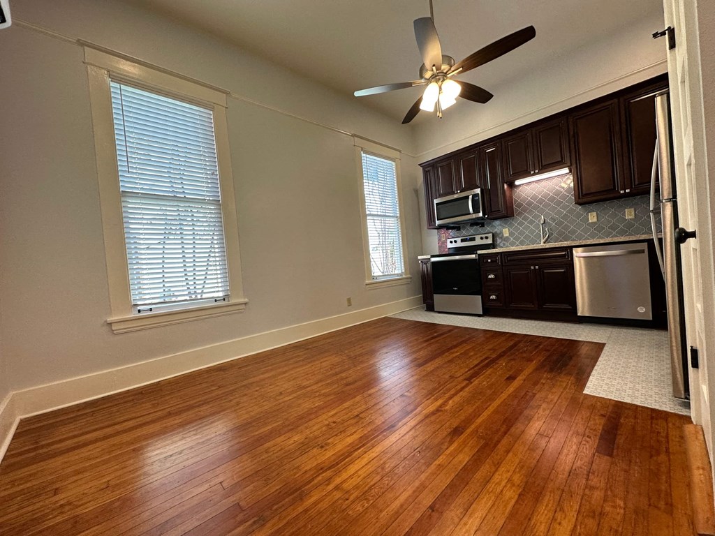 a kitchen and living room with wood floors and a ceiling fan