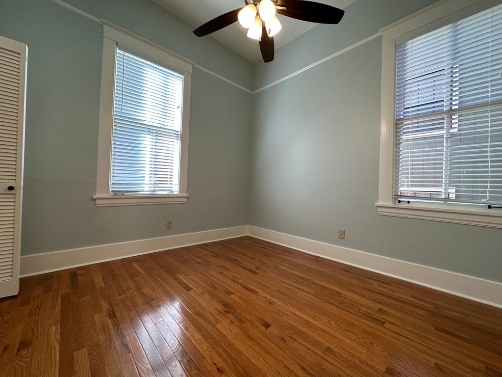 an empty bedroom with wood floors and a ceiling fan