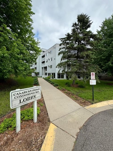 a sign on the side of a sidewalk in front of a building