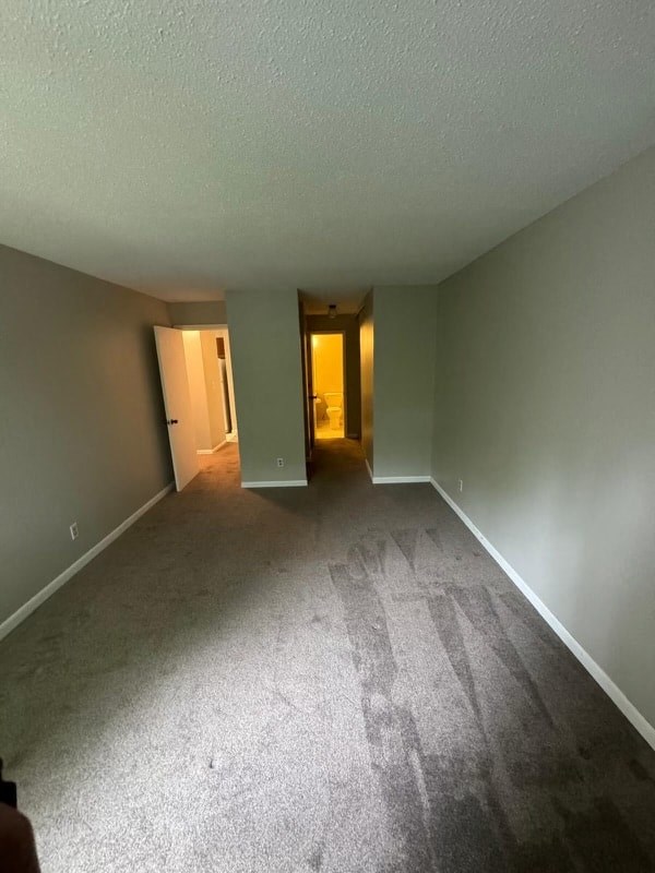 a living room with a carpeted floor and an empty room