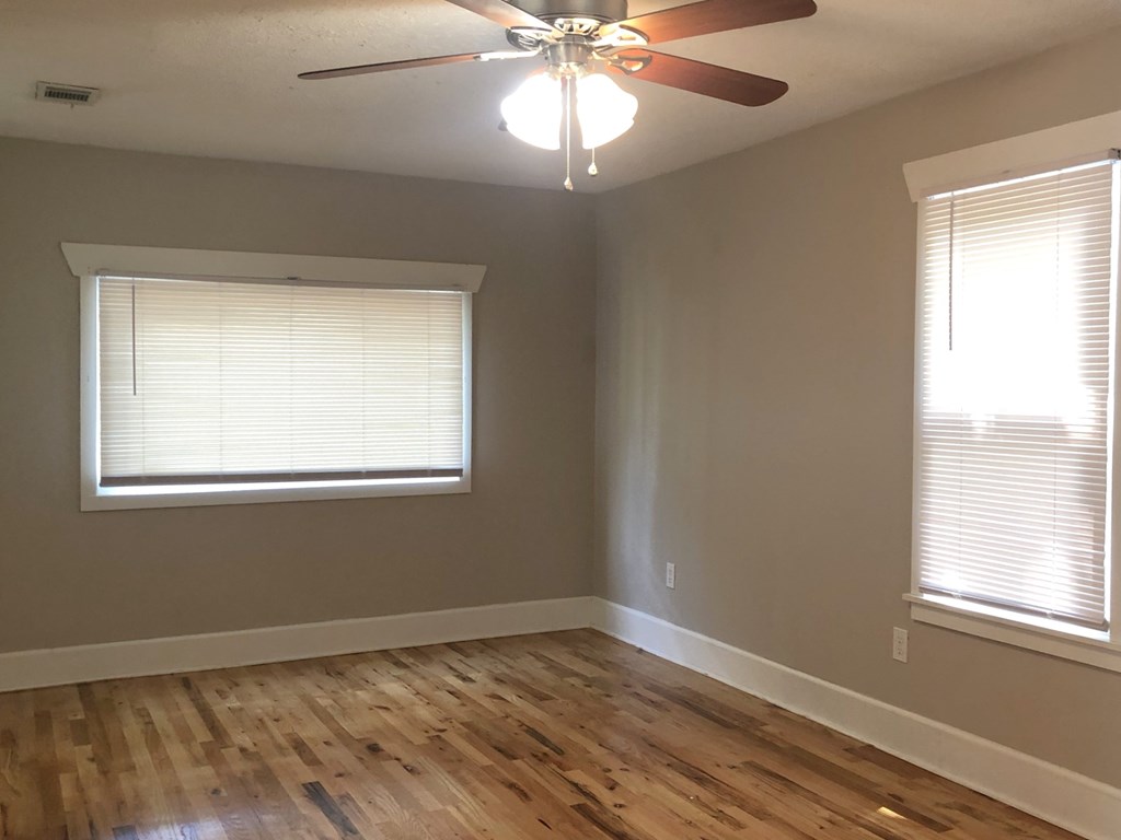 a living room with a ceiling fan and two windows