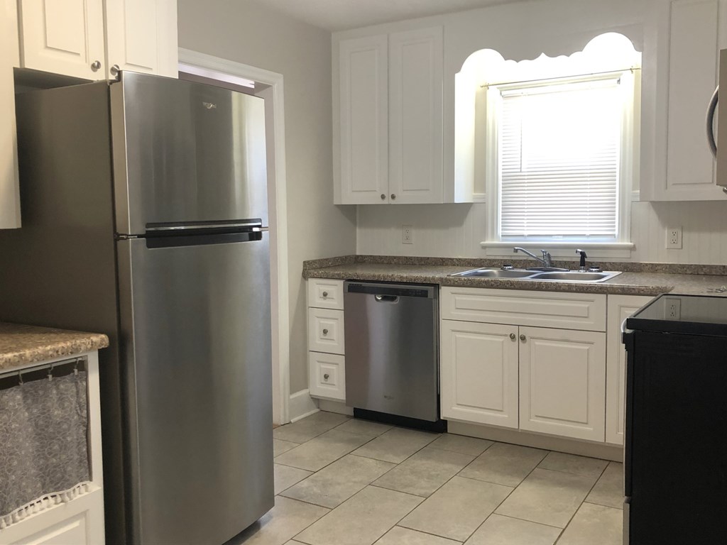 a kitchen with white cabinets and a stainless steel refrigerator