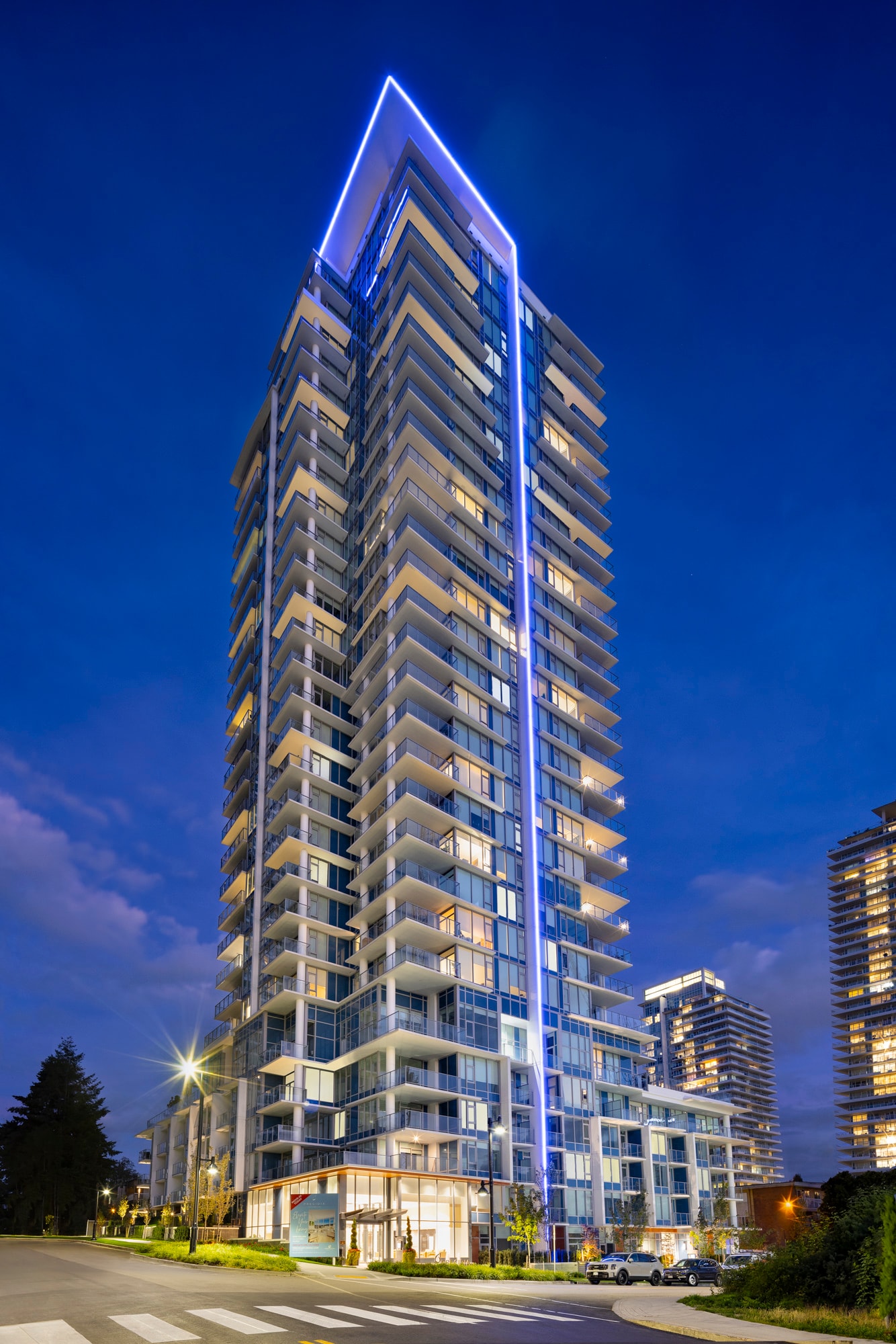 A tall, modern building with a blue light on the top is illuminated at night.