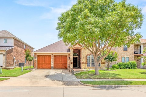 the front of a house with a garage and a tree