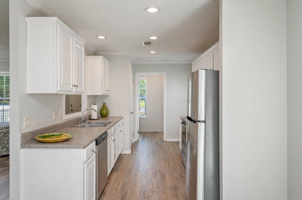 an empty kitchen with white cabinets and a stainless steel refrigerator