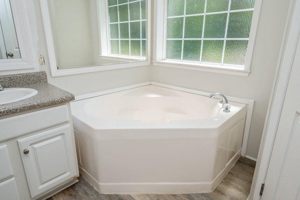 a bathroom with a tub and a sink and a window