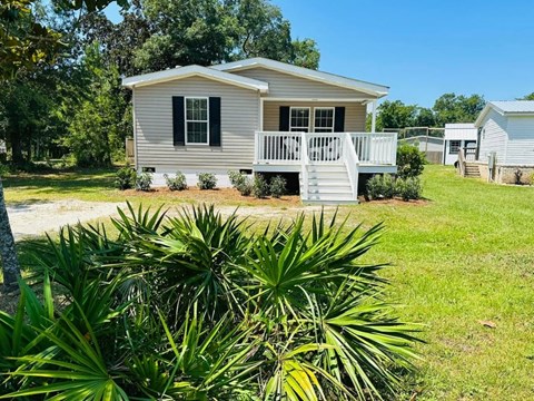 a small house with a porch and a yard with plants