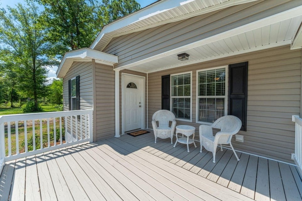 a covered porch with two chairs and a table on it