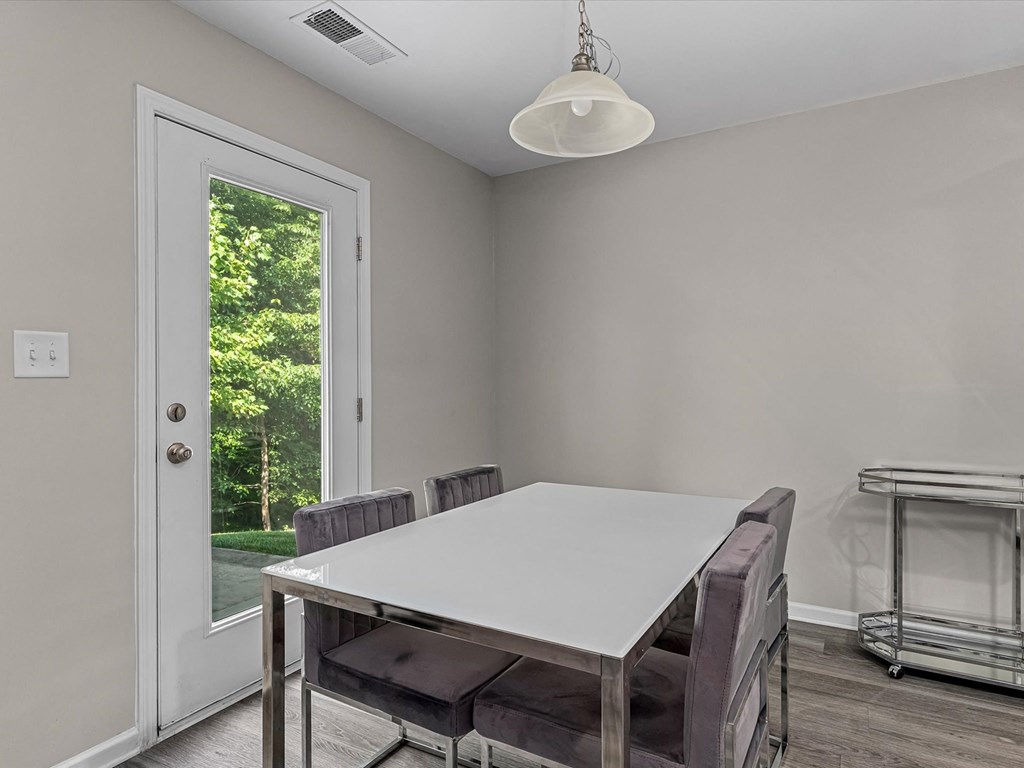 a dining room with a white table and chairs and a door to a backyard