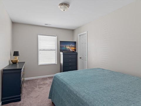 a bedroom with a bed and a dresser and a window