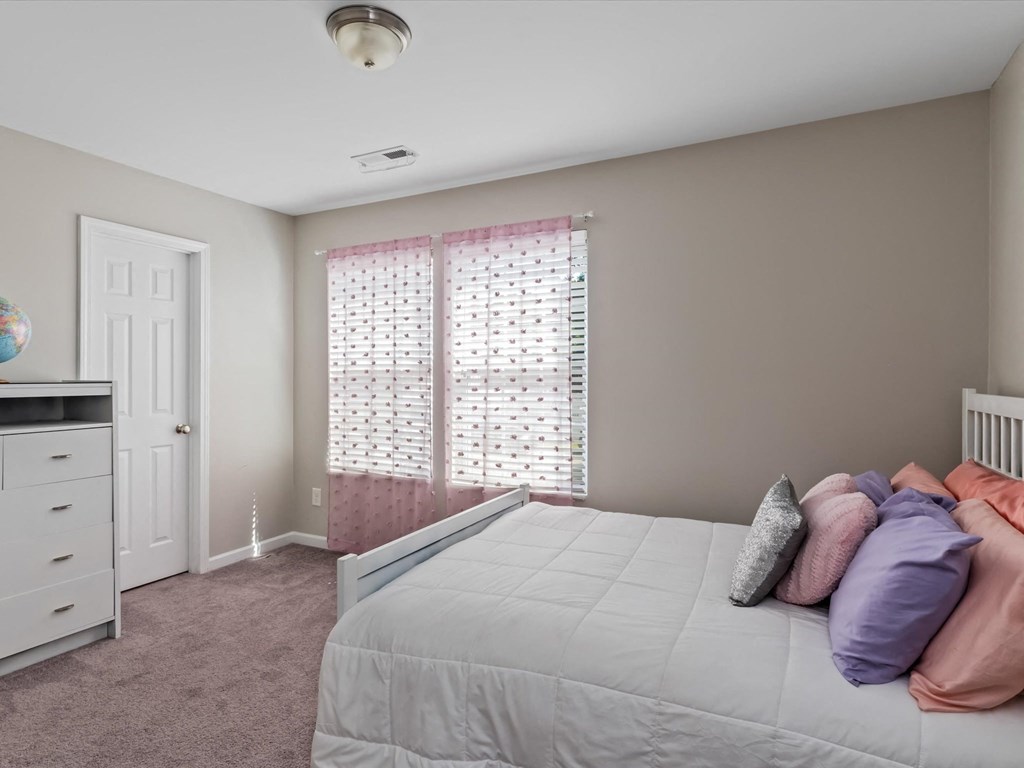 a bedroom with a large bed and a window with curtains
