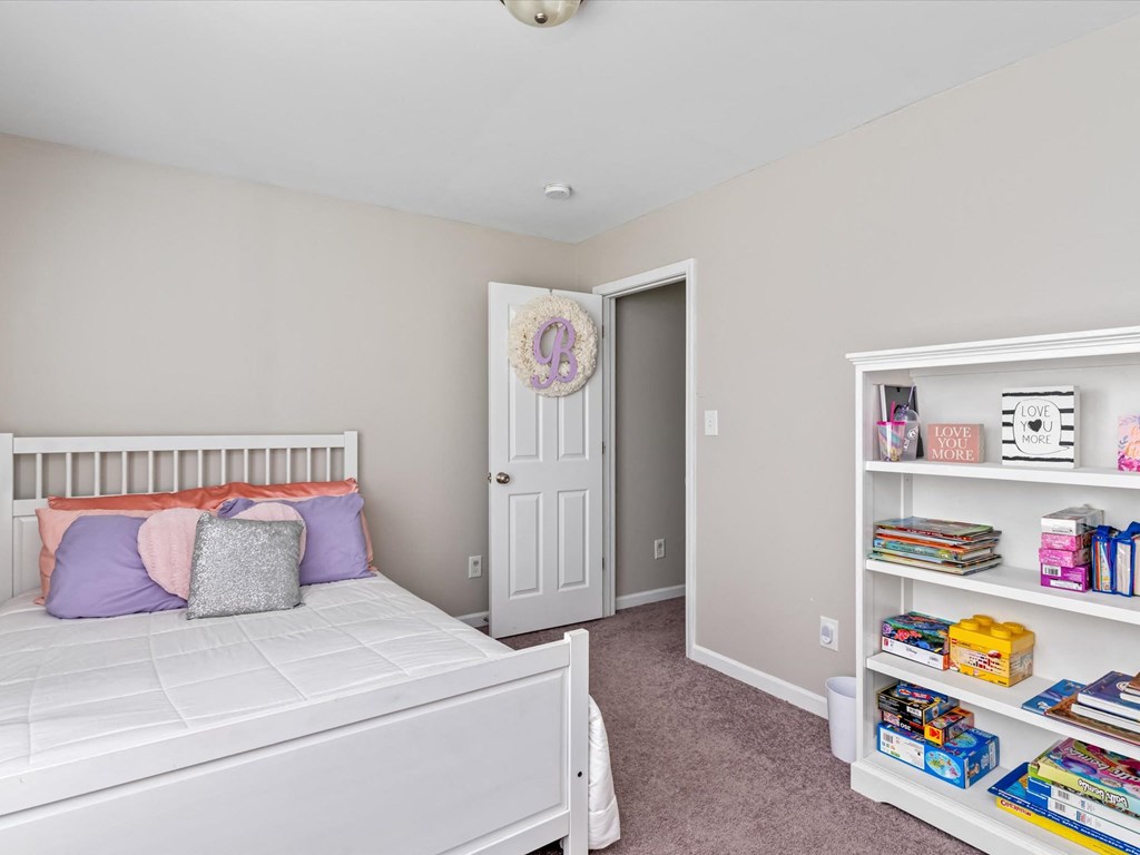 a bedroom with a white bed and a white book shelf