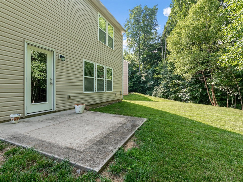 a patio in front of a house with grass and trees