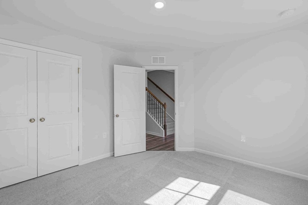 an empty room with two doors and a staircase in the background