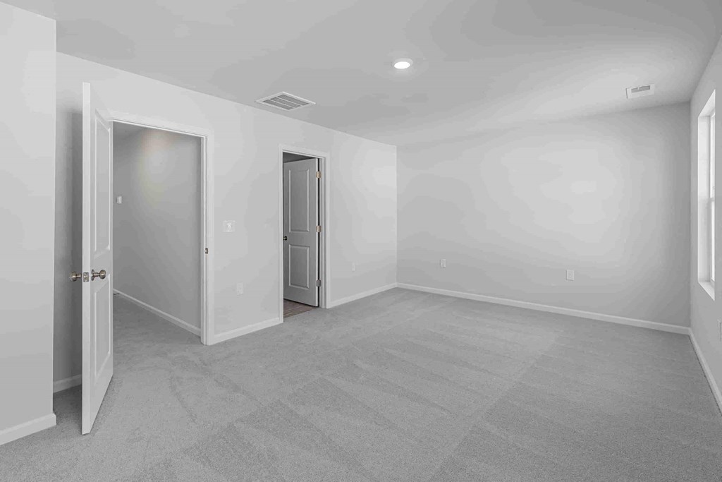 an empty bedroom with a door to a closet