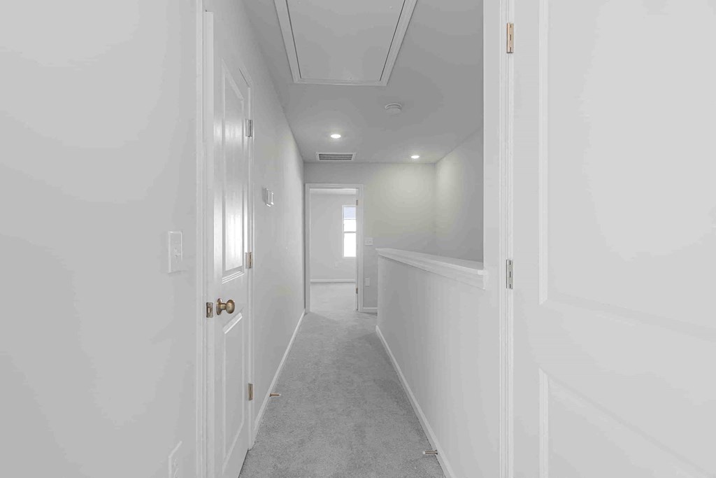 a long white hallway with white walls and a white door