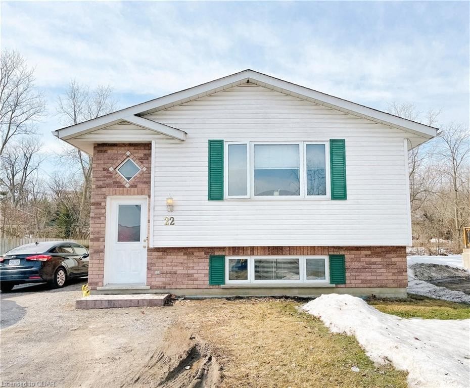 a small white house with green shutters and a parking lot