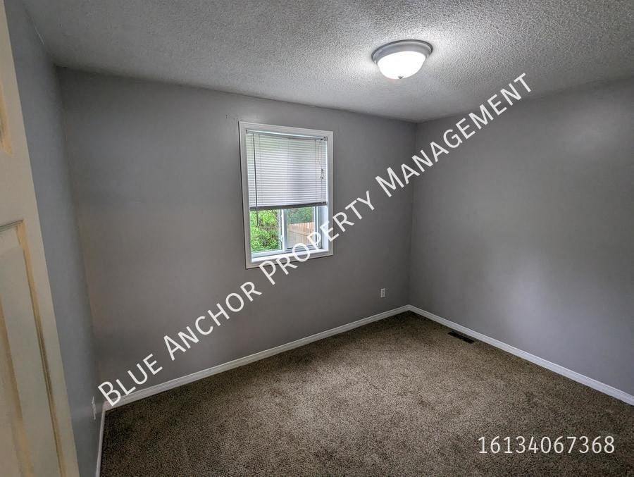 an empty bedroom with a window and carpet