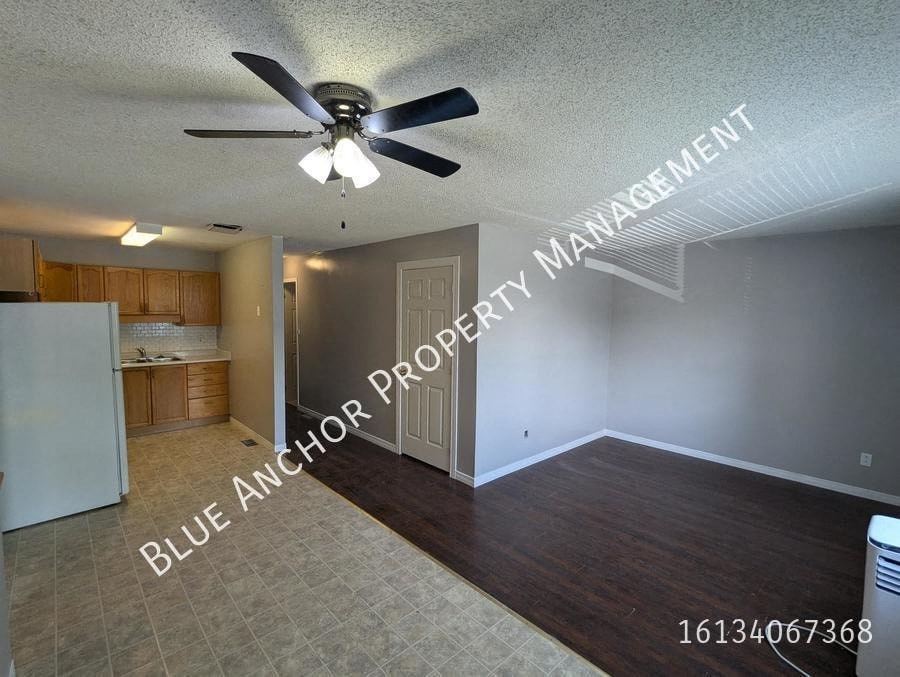 an empty living room and kitchen with a ceiling fan