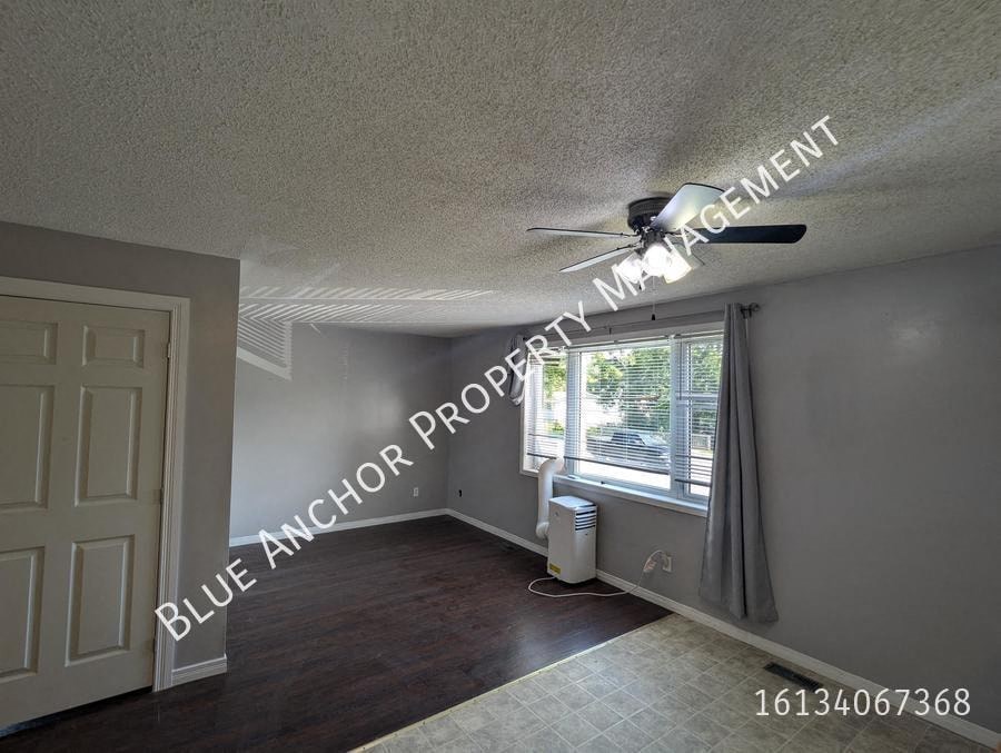 an empty living room with a ceiling fan and a window