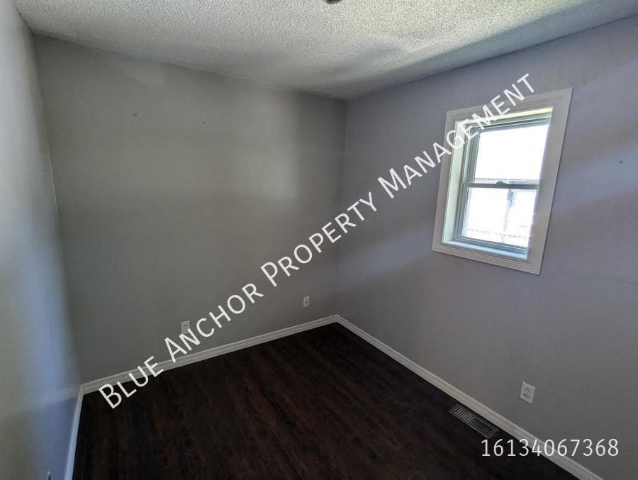 an empty room with a window and wooden floors