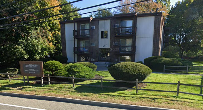 an apartment building with a sign in front of it