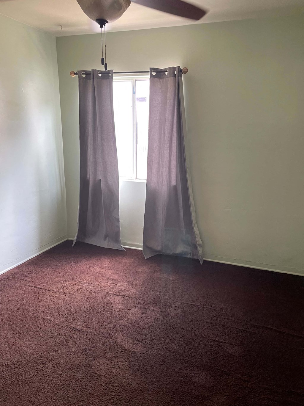 an empty room with two curtains and a window