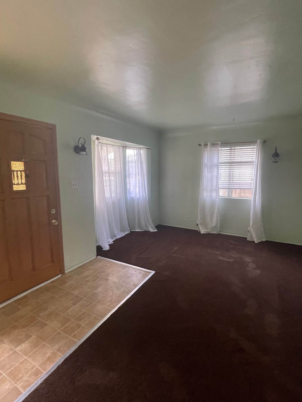 an empty living room with a door and curtains